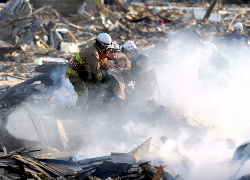 A resident is rescued from debris in the northern Japanese city of Natori on Saturday, one day after the powerful magnitude-8.9 quake struck.