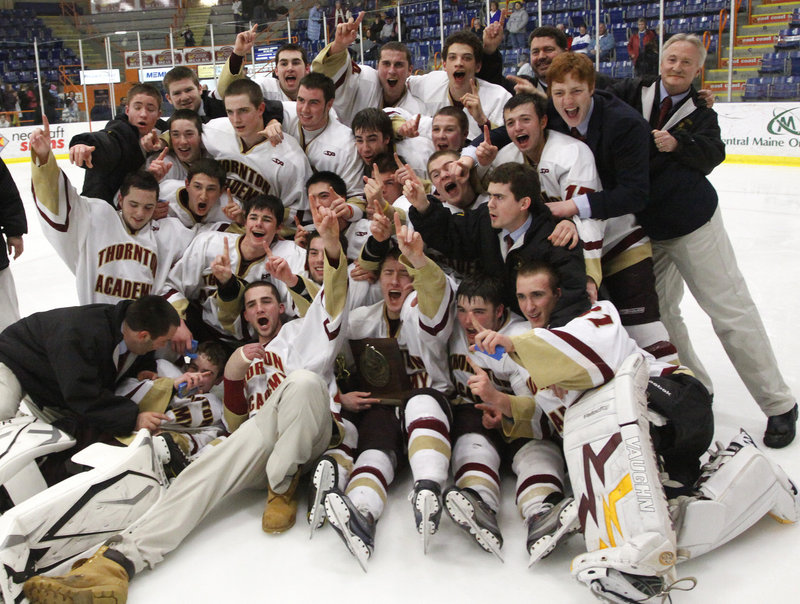 The Thornton Academy hockey team poses with the state Class A championship plaque Saturday after beating Lewiston 4-3 in double overtime. The Trojans won their first trip to the state final, as the Blue Devils lost in the state championship game for a fifth straight season.