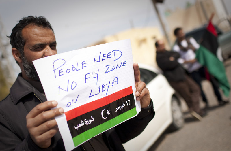 A Libyan man holds up a sign asking for a no-fly zone over Libya near the town of Musa’id on Sunday. Moammar Gadhafi’s forces swept rebels from one of their final strongholds on Libya’s main coastal highway, after waves of strikes from warships, tanks and warplanes.