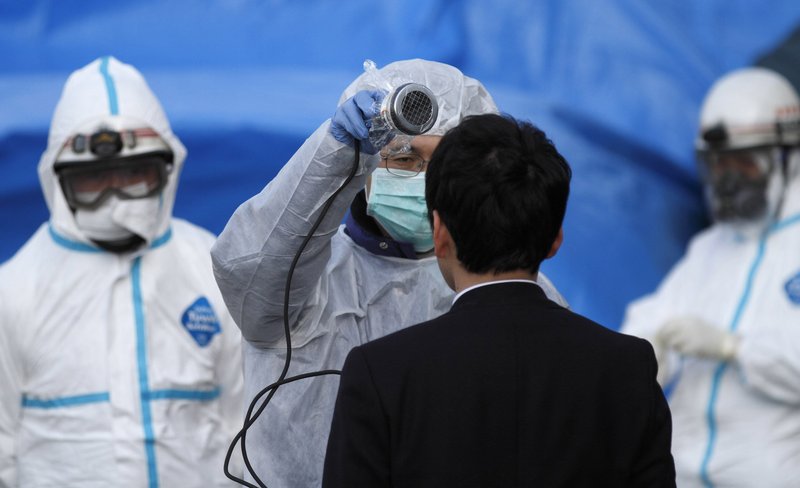 A worker scans a man for radiation exposure in Koriyama, Japan, on Sunday. So far, about 160 people show signs of exposure.