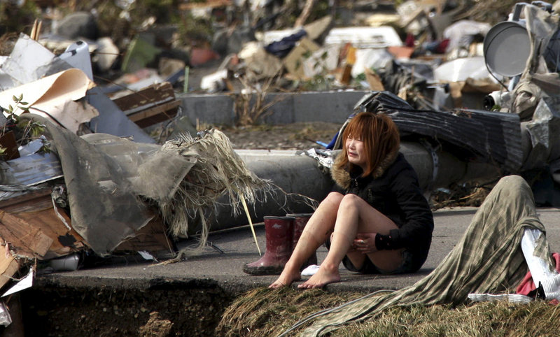 A woman breaks down Sunday amid debris left by Friday’s earthquake and tsunami in Natori, in northern Japan. In the town of Minamisanrikucho, 10,000 people – nearly two-thirds of the population – have not been heard from since the tsunami wiped it out.