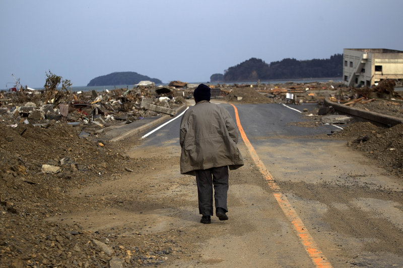 A survivor of the Japanese earthquake and tsunami walks alone on a road past the destroyed village of Saito, in northeastern Japan, on Monday. The tsunami that devastated Japan's coast rolled in through a tree-lined ocean cove and obliterated nearly everything in its path, wiping out the village of about 250 people and 70 houses.