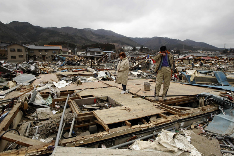 Keijo Nakamura, right, and his wife, Haruka, stand Tuesday in Ofunato, Japan, on the remains of a dead relative’s home, which had been washed away by last Friday’s tsunami. The U.S. and United Kingdom deployed 220 rescue team members to the town to hunt for trapped survivors Tuesday.