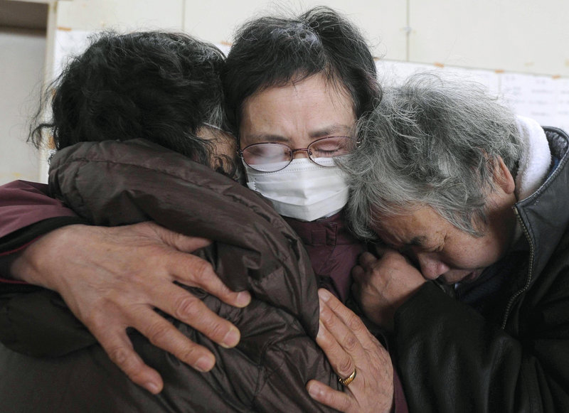 Survivors huddle in mourning at a Kesennuma, Japan, evacuation center after learning Tuesday of the death of relatives in the quake and tsunami.