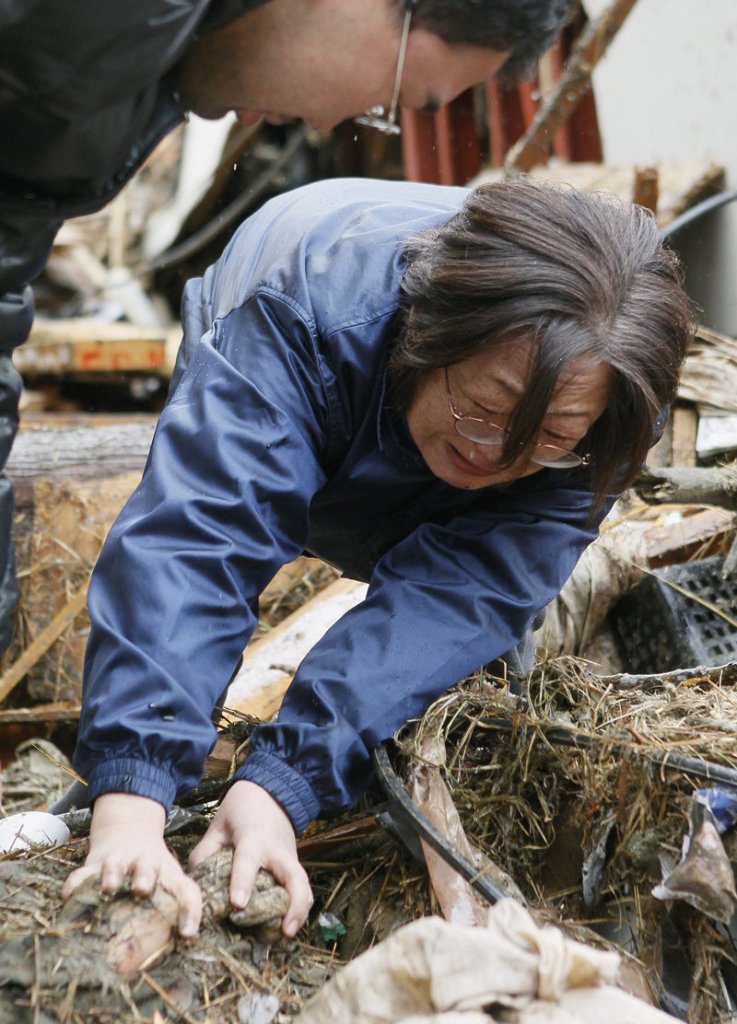 Yoshie Murakami weeps Wednesday as she holds her deceased mother’s hand in the rubble near where her home used to stand in Rikuzentakata, Japan.