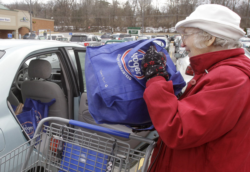 Lynne Curtiss places reusable Kroger bags in her car after shopping in Cincinnati. The grocery chain has eliminated a bonus for shoppers using their own bags.