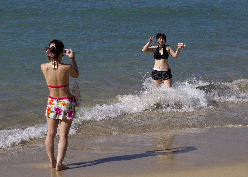 Two visitors from Japan take pictures at Waikiki Beach in Honolulu on March 11. Hawaii is bracing for a loss in tourists from Japan as a consequence of the earthquake, tsunami and nuclear crisis in that nation.