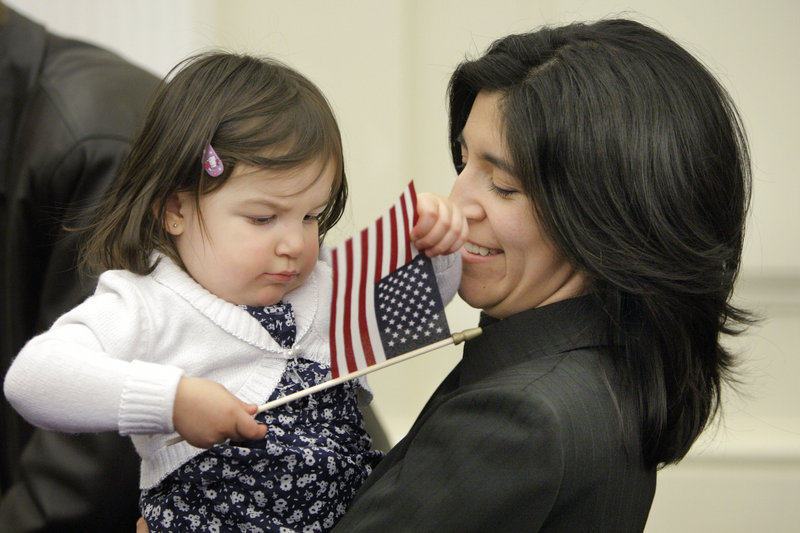 Sofia Short, 2, plays with a flag her mother, Clara, received after being sworn in as a new U.S. citizen.