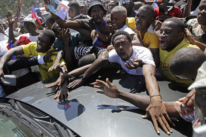 Energized supporters of Haiti’s former president, Jean-Bertrand Aristide, surround his car as Aristide arrived at his home in Port-au-Prince, Haiti, on Friday, after seven years in exile.