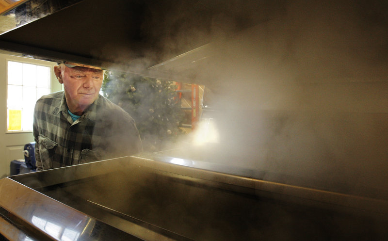 Bob Michaud checks on sap boiling in an evaporator at the Thurston and Peters Sugarhouse in Newfield.