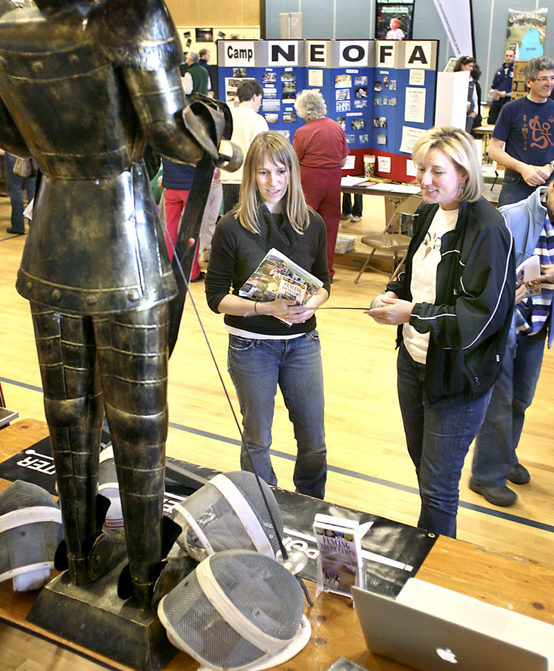 Nancy Reynolds, right, owner of Fencing Youth Camps in Westbrook, talks to Tennyson Towl of South Portland during the camp fair Sunday at Portland’s East End School. Parents and children had the chance to visit with representatives of 70 camps and summer programs.