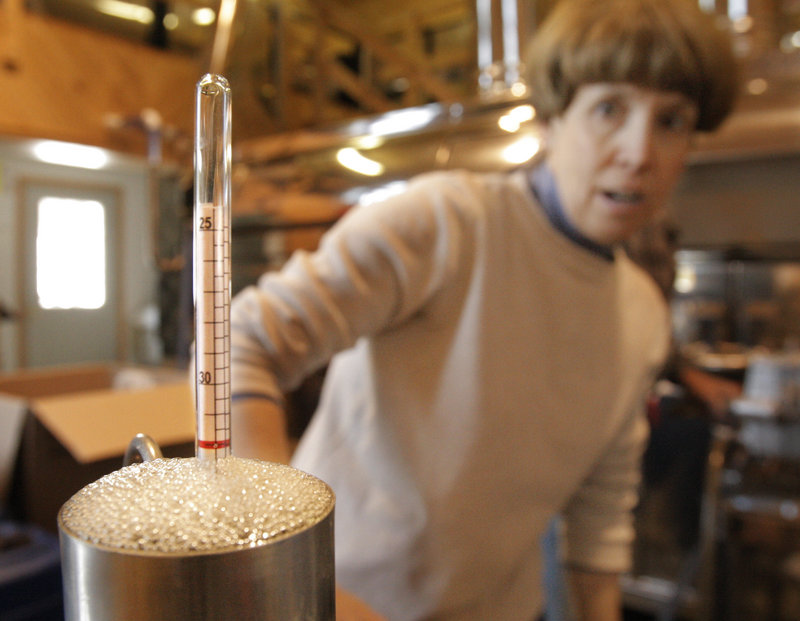 Debra Hartford looks at a hydrometer to check the density of syrup that is about to be bottled at the Thurston and Peters Sugarhouse.