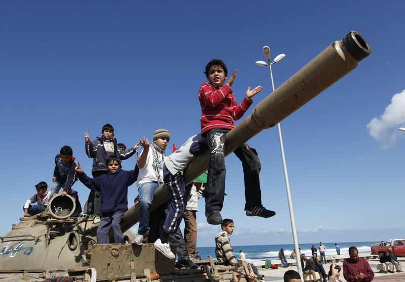 Libyan boys sitting on the cannon of a destroyed army tank celebrate the freedom of Benghazi on Monday. U.S., British and French warplanes, enforcing a U.N. resolution, bombarded government armored vehicles as they fled the city Sunday.