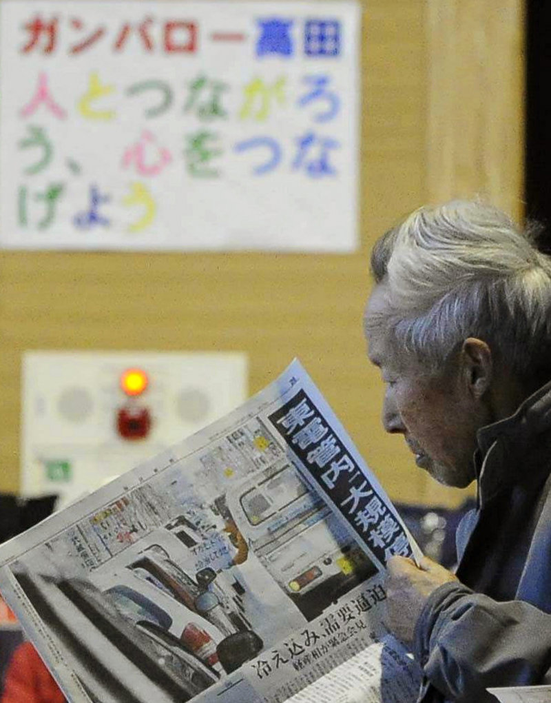 An elderly woman reads a newspaper at an evacuation center in Rikuzentakata, Iwate prefecture, in northeastern Japan, on Friday. Lacking access to modern media, and with residents in need of information, one newspaper, the Hibi Shimbun in Ishinomaki, wrote its articles by hand with black felt-tip pens on big sheets of white paper. It missed publication only for two days after the earthquake and tsunami.