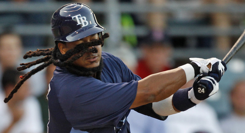 With his dreadlocks wrapped around his face, Tampa Bay’s Manny Ramirez swings and misses at a pitch during the second inning of a spring training game Tuesday against Boston in Fort Myers, Fla. Ramirez walked on the at-bat.