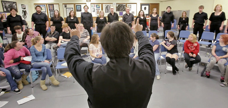 Professor Robert Russell conducts the USM Chamber Singers at Kennebunk High School on Wednesday, as middle school and high school students listen. “They used to say that USM is the best-kept secret. We want to counter that,” he said.
