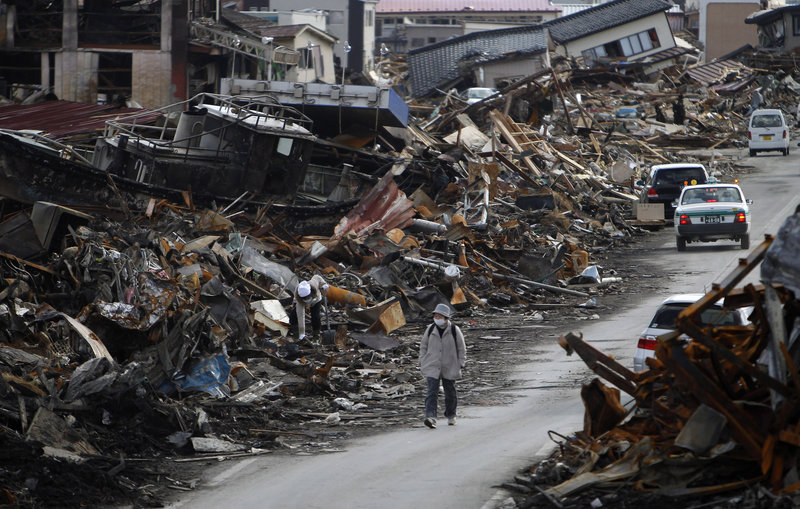 A resident of Kesennuma, Miyagi Prefecture in northern Japan walks between the rubble caused by the March 11 tsunami. Some 660,000 households still do not have water, the government said.
