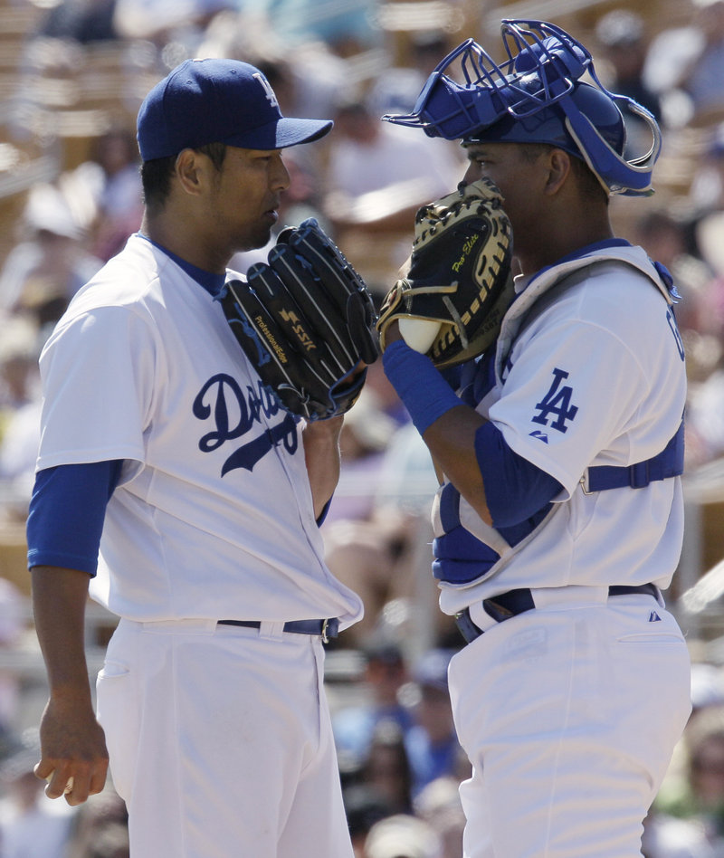The Dodgers’ Hiroki Kuroda, left, and catcher Hector Giminez are awfully secretive for a spring training game. It didn’t help as Colorado scored seven times in the ninth inning for a 7-5 win.