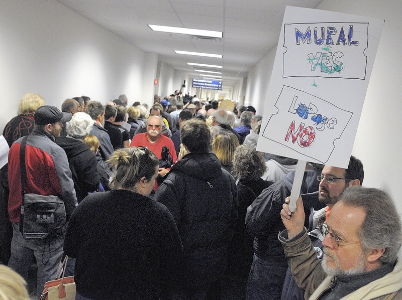 Roy Patterson, right, of Gray holds a sign expressing his feelings as hundreds of protesters listen to speeches at a noon rally Friday at the Department of Labor in Augusta. The event was organized by the Maine Union of Visual Artists and the Maine AFL-CIO to protest Gov. Paul LePage’s order to remove a 36-foot, 11-panel mural from the building. The artwork, by Judy Taylor of Tremont, was installed in 2008.