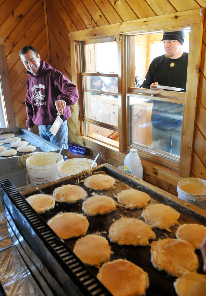 Clint Harris cooks pancakes as Denis Clark of Saco awaits a second helping at a window during Maine Maple Sunday at Harris Farm in Dayton on Sunday.