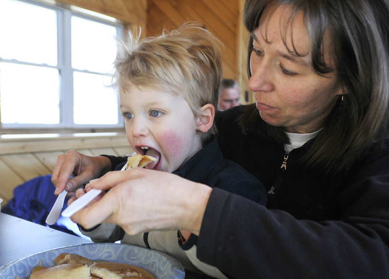 Aaron Pickering, 3, of Kennebunk takes a big bite of a pancake with the help of his mother, Kathy Pickering, during Maine Maple Sunday at Harris Farm in Dayton.