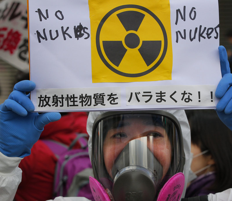 A protester in a protective mask holds a placard during an anti-nuclear rally in Tokyo on Sunday. The nuclear plant crisis has spurred concerns about the safety of food and water in Japan. Radiation has been found in food, seawater and even tap water supplies in Tokyo.