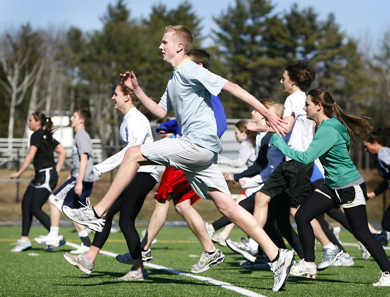 Evan Eklund and his Falmouth High track teammates participate in warmup drills Monday at Falmouth High School. Coach Dan Paul greeted more than 100 athletes on the first day of practice.