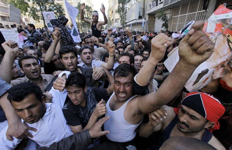 Pro-government protesters shout slogans as they carry pictures of Syrian President Bashar Assad during a sit-in Sunday in front of the Syrian embassy in Beirut.