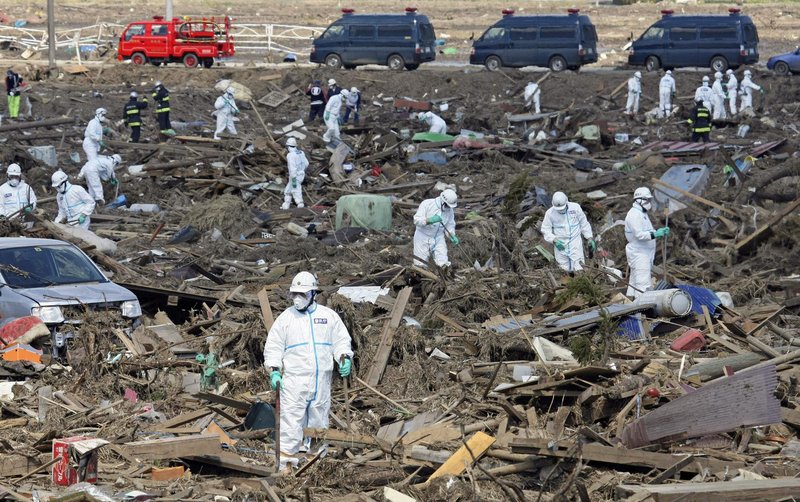 Tokyo Metro Police officers wearing protective suits search for the remains of victims of the giant tsunami triggered by the March 11 earthquake in Minamisoma, Fukushima prefecture, Japan, on Monday.