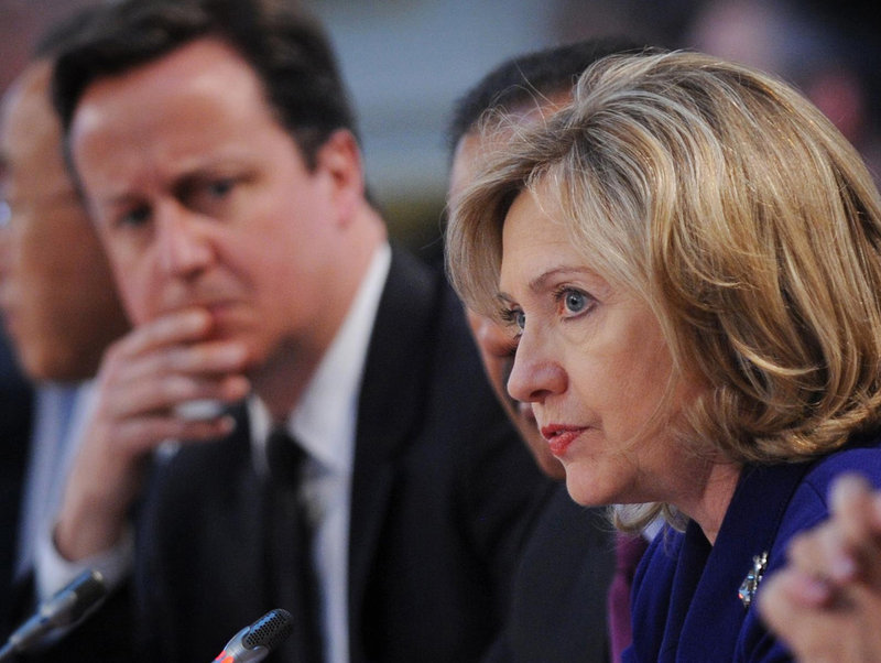 British Prime Minister David Cameron listens as U.S. Secretary of State Hillary Rodham Clinton speaks Tuesday at a conference on Libya in London. Forty world leaders attended the talks, seeking to ratchet up the pressure on Col. Moammar Gadhafi to step down. Gadhafi has lost the legitimacy to lead, so we believe he must go, Clinton said.