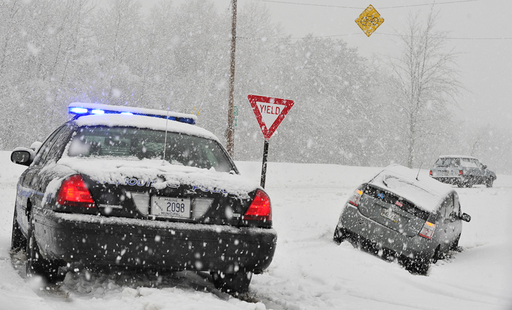 Snowfall is heavy as a Falmouth police officer arrives on the scene of a car that slid off Route 1 near Route 88 this morning at around 7:45.