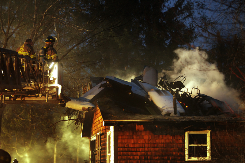Biddeford firefighters move a ladder closer to an airplane that crashed into a house on Granite Street Extension in Biddeford tonight.