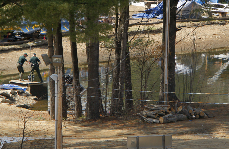 Investigators collect evidence at a snowmaking pond at Mount Cranmore in Conway today.