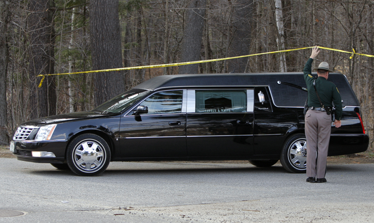 A New Hampshire State Police trooper holds up police tape so a hearse can pass underneath and leave Mount Cranmore in North Conway, N.H, today.