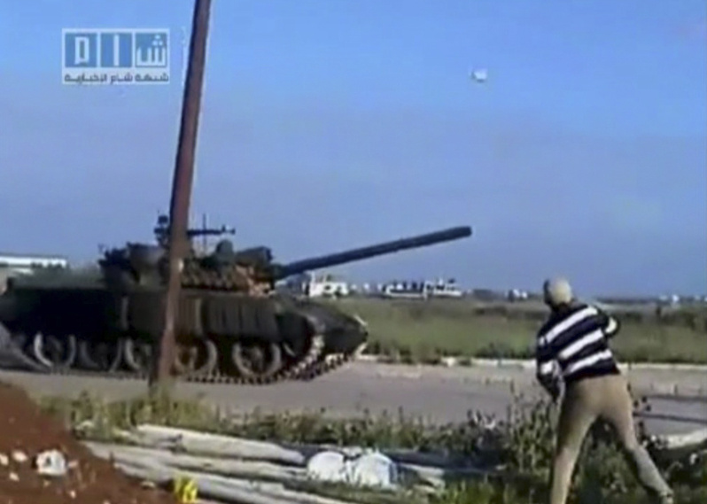 An image taken from amateur video shows a man throwing an object at a tank Sunday in Daraa, Syria. Troops and tanks stormed the town early Monday and opened fire, reportedly killing dozens of protesters.