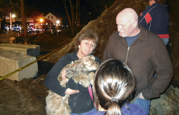 Kim Myers, left, holding her dog Jeneva, stands with her husband Steve as she talks to a reporter on Sunday.