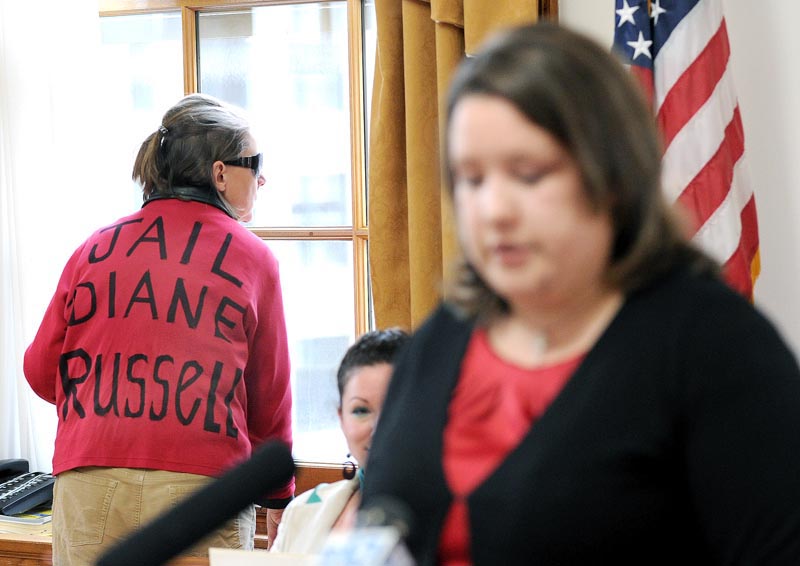 A lone protester who refused to give her name stands in the background as Rep. Diane Russell holds a press conference on her bill to legalize and tax marijuana.