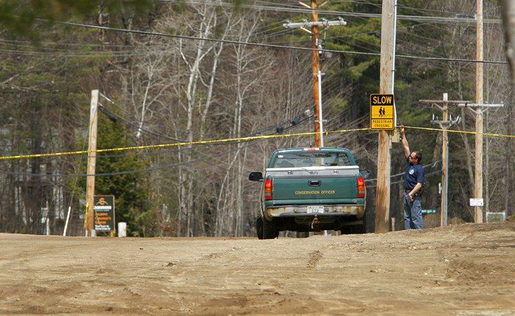 A man lifts police tape to let in a New Hampshire truck to the pond near the base lodge of Mount Cranmore in North Conway that was searched today. The pond, which is used for snowmaking, is near where Krista Dittmeyer's car was found.
