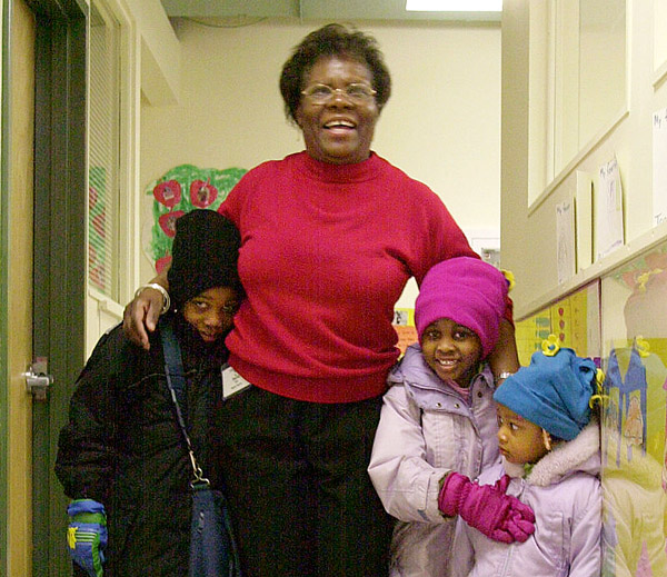 A teacher helps young children get ready to go home. Reaching kids this age early can pay dividends for decades.
