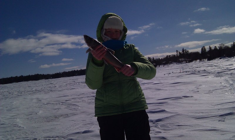 Jillian Beland of Augusta displays a 15-inch brook trout she caught at Moosehead Lake during a family trip in February.