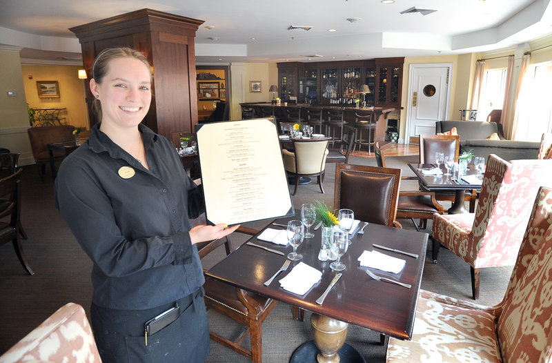 Server Kate Somerville displays a menu at Eve’s at the Garden, the restaurant at the Portland Harbor Hotel, where the service is door-to-door attentive.
