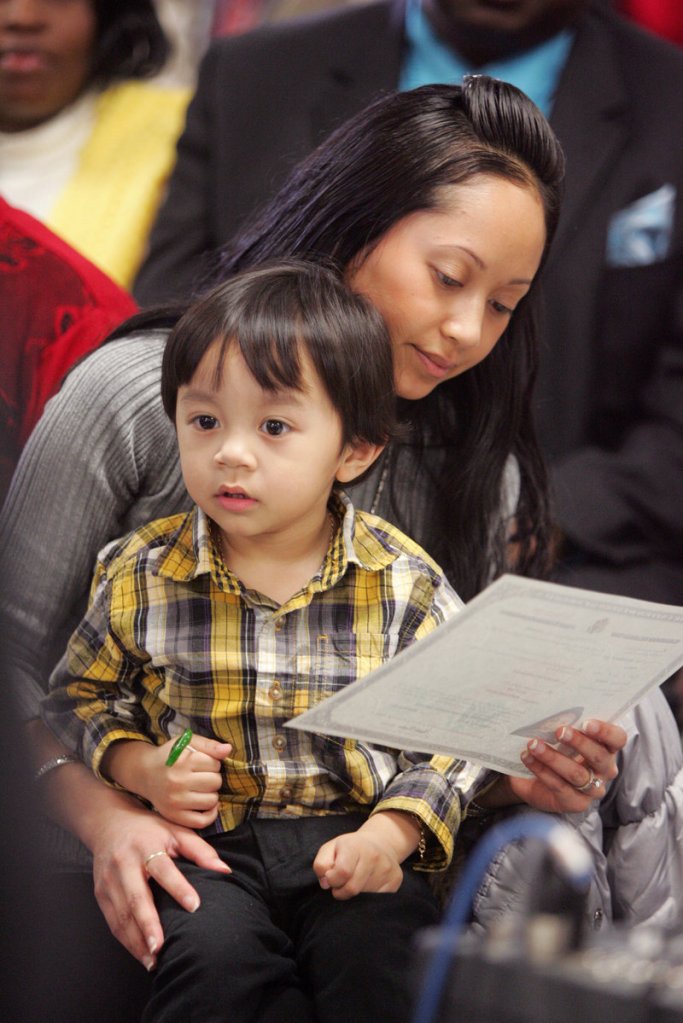 Alice Ker, originally from France, examines her naturalization certificate with her son, Kash, 3.