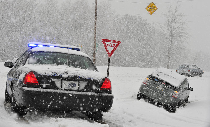 Heavy snow falls as a Falmouth police cruiser protects a car that slid off Route 1.