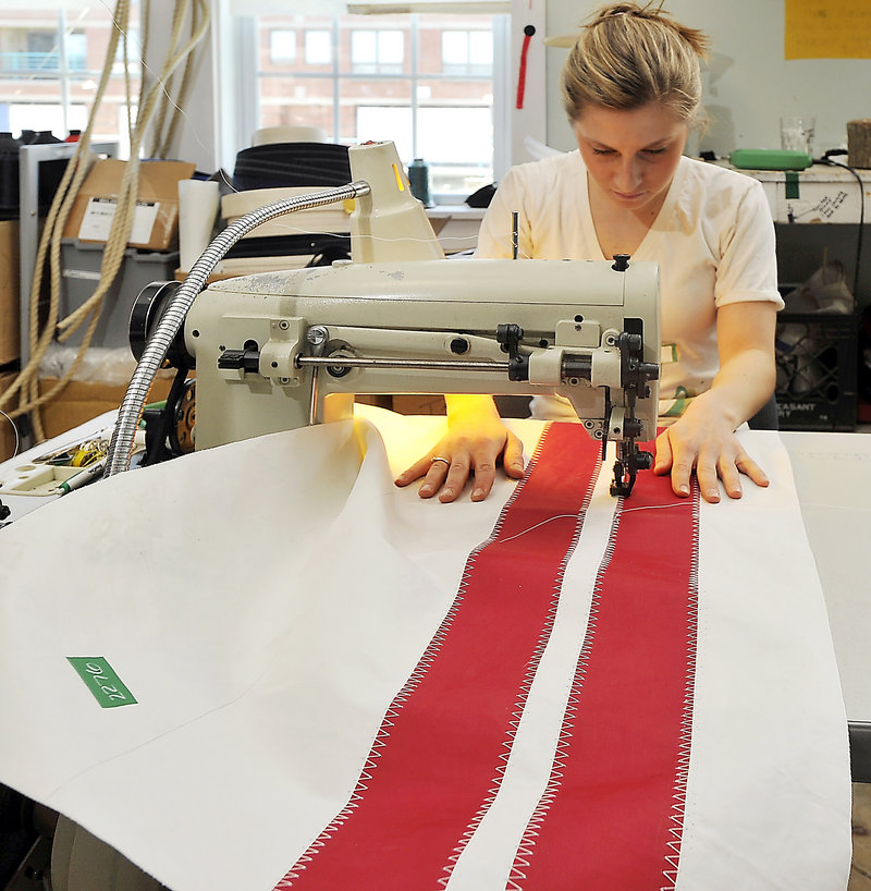 Seamstress Alaina Harris reinforces appliques that add decorative touches to the recycled sail panels that will become a tote bag at Seabags on Custom House Wharf in Portland.