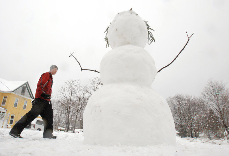 Nate Ruel carries rocks to be used as eyes and buttons on a 7-foot snowman he built Friday on Day Street in Kennebunk. The wind and heavy, wet snow caused 25,000 CMP customers to lose power at one point in the afternoon.
