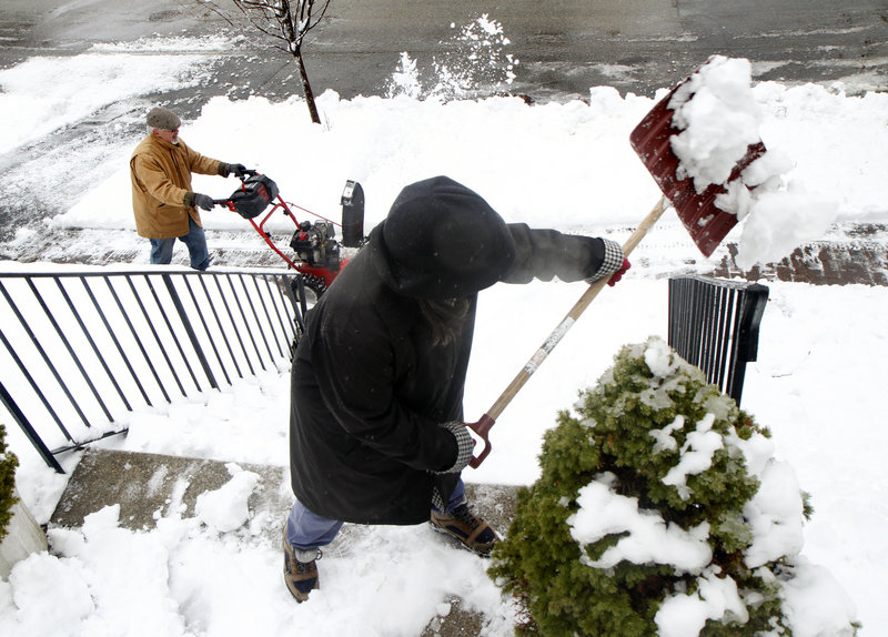 Kate Lesser and her husband, James Pierce, team up to clear the snow Friday at their home on Orland Street in Portland. While the city got 5.9 inches, the record for an April 1 snowfall is 11.1 inches, set in 1922.