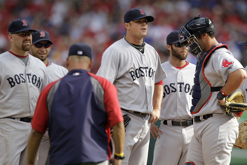 Red Sox pitcher Jon Lester, center, awaits word from manager Terry Francona, foreground left, who removed him from the game in the sixth inning of Boston’s season opener Friday against the Texas Rangers in Arlington, Texas. Also pictured are teammates, from left, Kevin Youkilis, Marco Scutaro, Dustin Pedroia and Jarrod Saltalamacchia. The Rangers won, 9-5.
