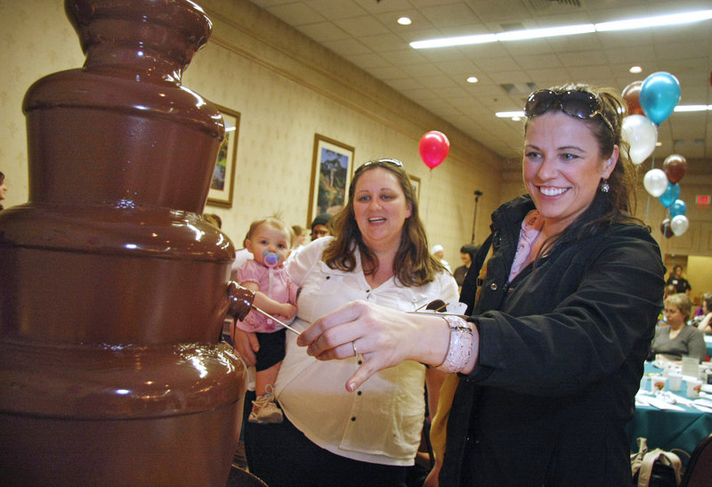 Candice Noble of Lyman dips a marshmallow into chocolate while Dawn Hamilton of Waterboro and her 11-month-old daughter, Emma, watch at the Chocolate Falls in Maine fountain on display at the Chocolate Lovers’ Fling at Holiday Inn by the Bay in Portland on Sunday. The event benefits Sexual Assault Response Services of Southern Maine.
