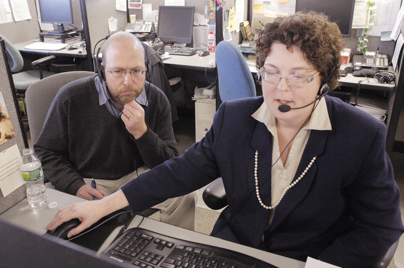 Ray Routhier listens to Mary Aubele, a financial counselor with the Institute for Financial Literacy in South Portland, help a client on the phone.