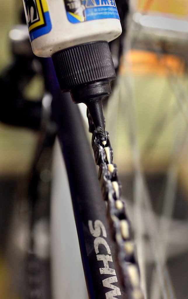 Morin applies lubrication to a chain as he gives a bicycle a tune-up. A clean chain lasts longer and shifts smoother.